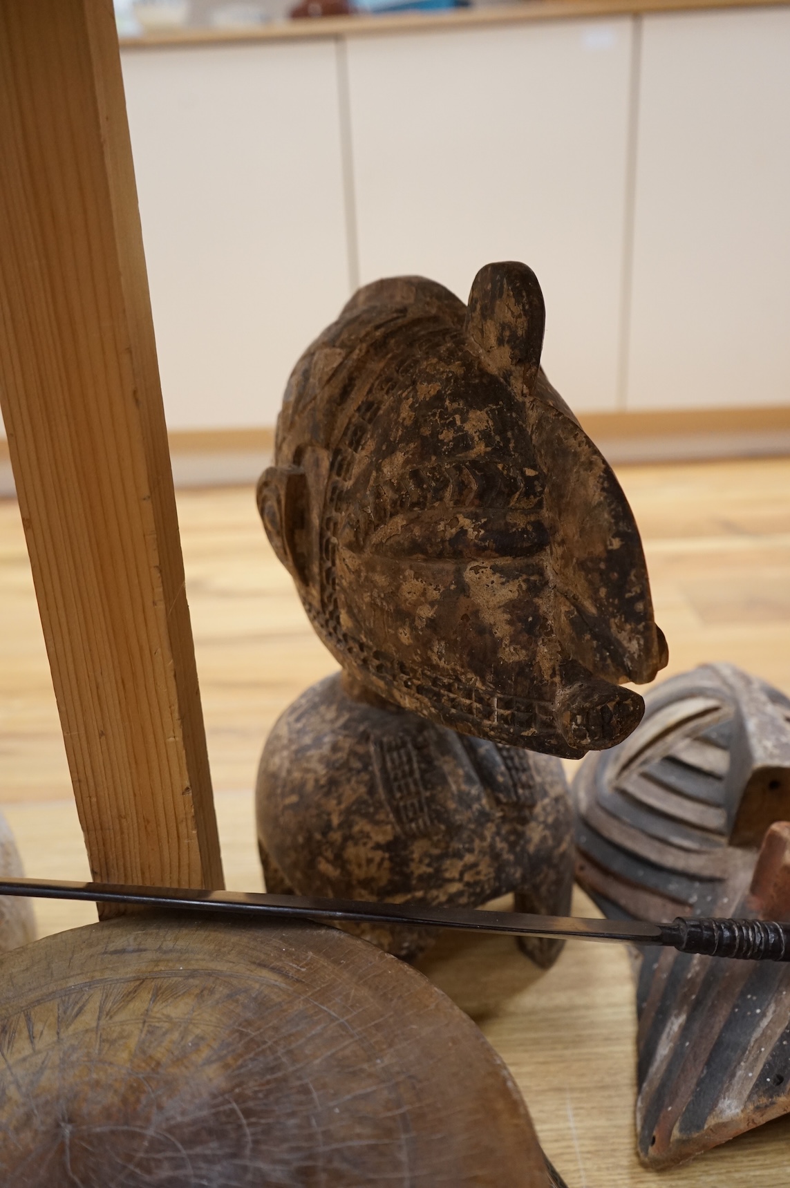 An eclectic group of tribal carvings to include a stool, various weapons, masks, etc, largest mask 52cm high
